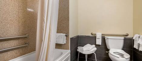 A bathroom with a bathtub, toilet, and handrails.