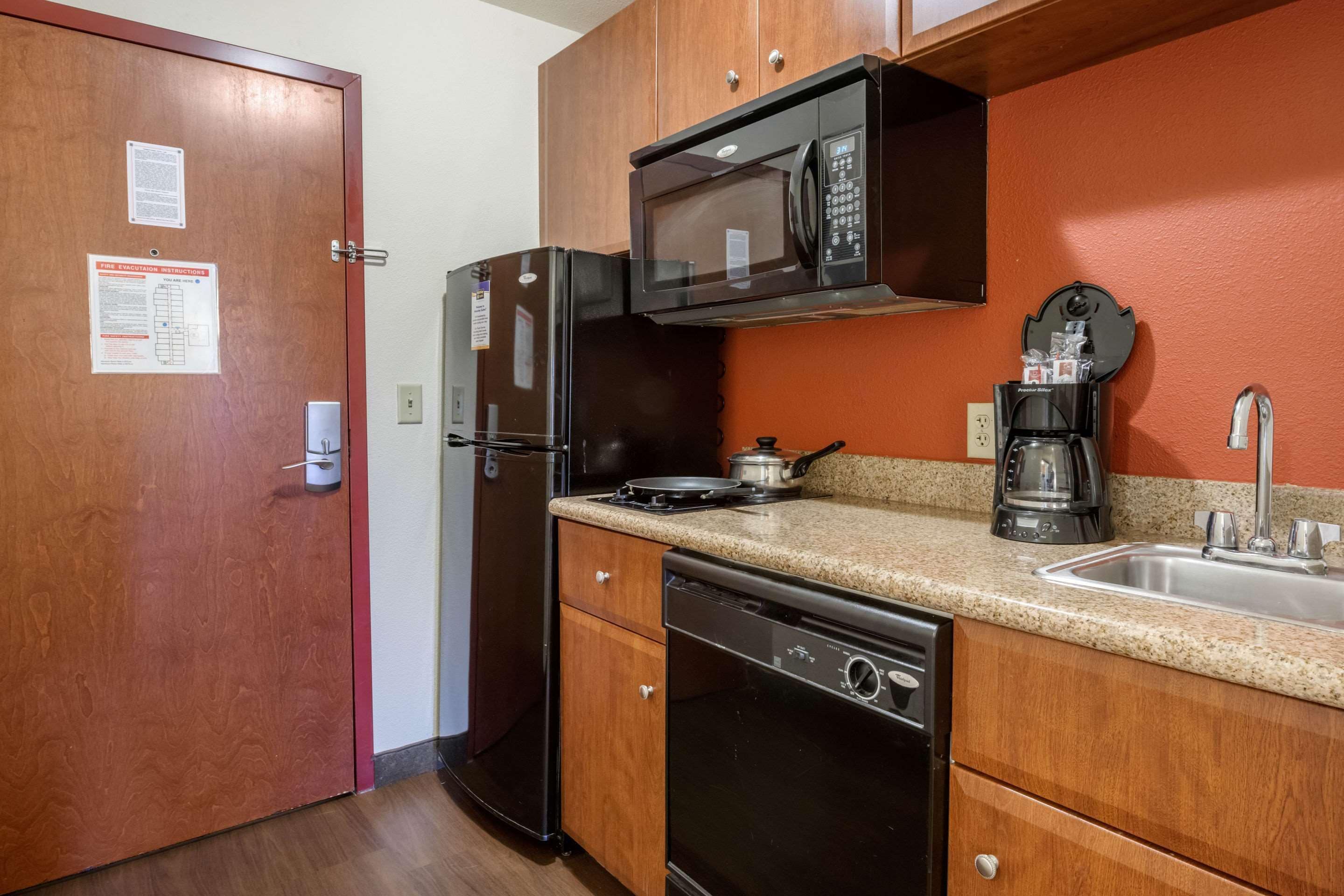 Una cocina compacta equipada con refrigerador, microondas, estufa, lavavajillas y cafetera.