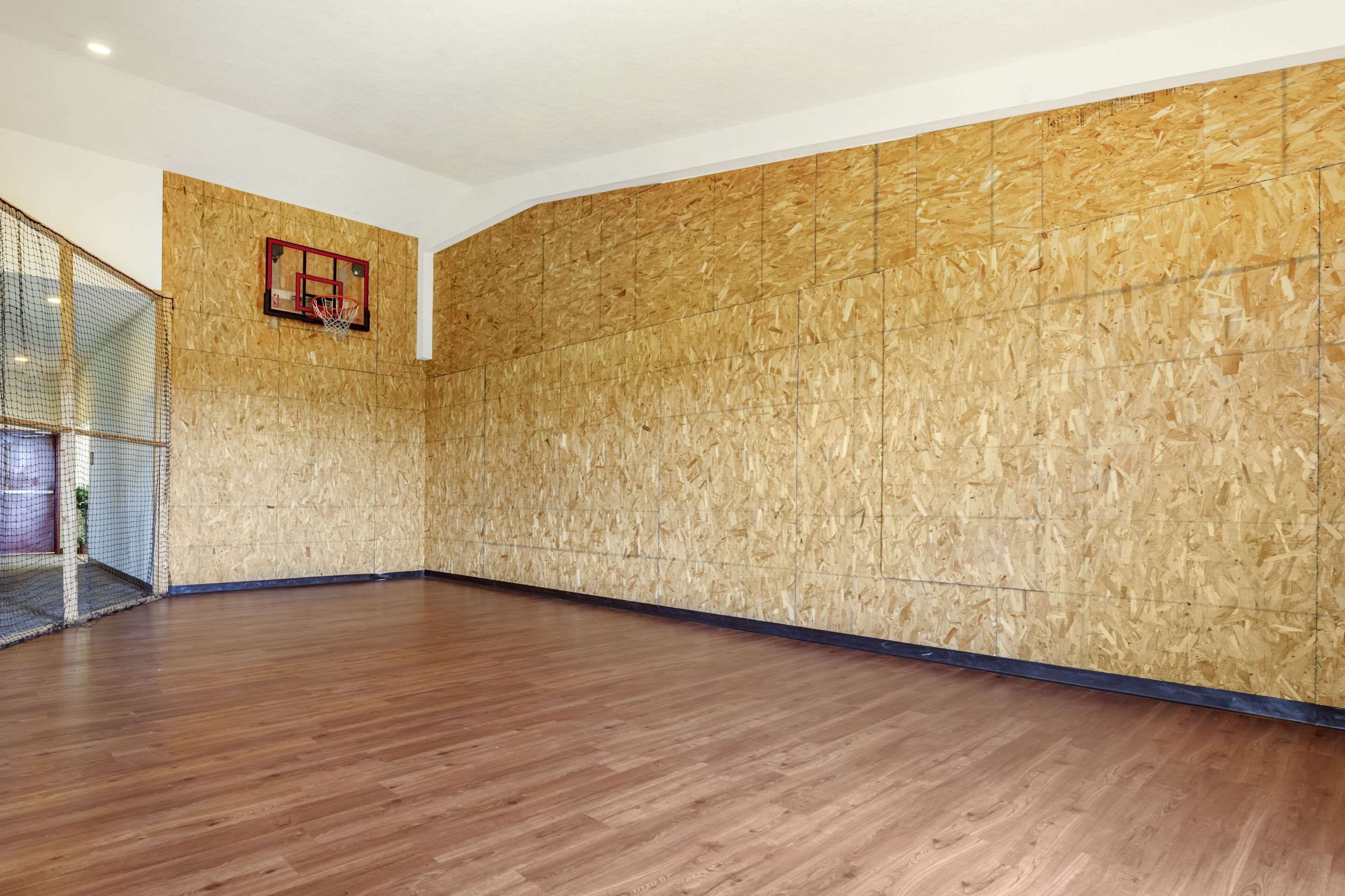 Un grand espace intérieur doté d’un plancher en bois et d’un panier de basket fixé au mur.