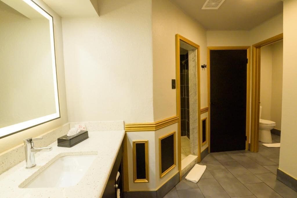 A bathroom with a large mirror, a sink, and a toilet.