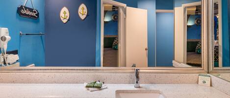 Un baño con un espejo grande, un lavabo y un perchero para toallas.