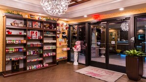 A hotel lobby with a large teddy bear statue, shelves stocked with various items, and a chandelier. - Inn of the Dove Romantic Suites with Jetted Tub & Fireplace (Bensalem)