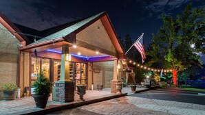 A hotel with a covered outdoor area, a flag, and decorative lights. - Inn of the Dove Romantic Suites with Jetted Tub & Fireplace (Bensalem)