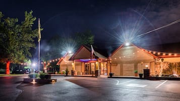 A hotel with a stone facade, a flag, and a well-lit entrance.