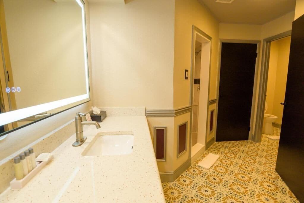 A bathroom with a large mirror, a sink, and a toilet.