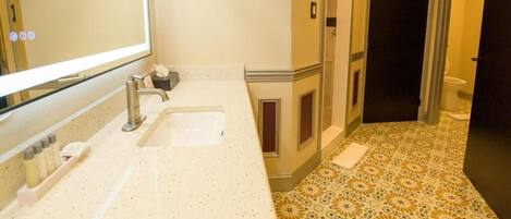 A bathroom with a large mirror, a sink, and a toilet.
