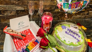 Une table décorée pour un anniversaire, avec un gâteau, une rose, une bougie et une carte de vœux.