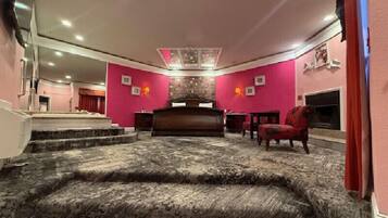 A living room with a fireplace, a red chair, and a patterned carpet.