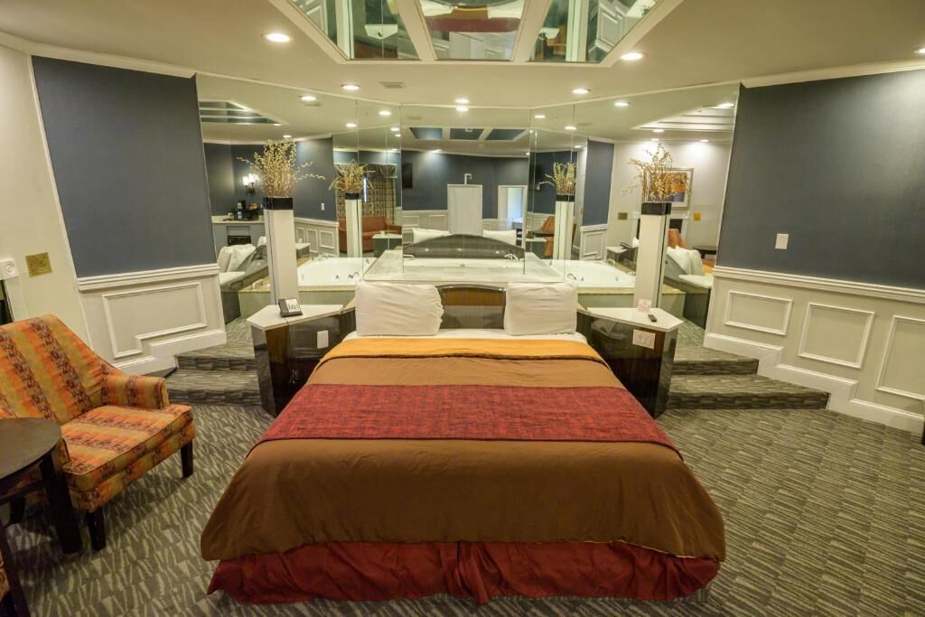 Habitación de hotel con una cama grande, una silla, un escritorio y un espejo.