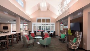 A spacious lobby with high ceilings, large windows, and a variety of seating options including chairs and tables. - Residence Inn by Marriott Dallas Arlington South (Arlington)