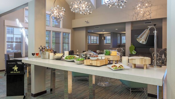 A buffet setup with various food items and a sign indicating 'Off the Grill' service. - Residence Inn by Marriott Dallas Arlington South (Arlington)