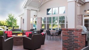 An outdoor patio area with wicker furniture, a fire pit, and a grill. - Residence Inn by Marriott Dallas Arlington South (Arlington)
