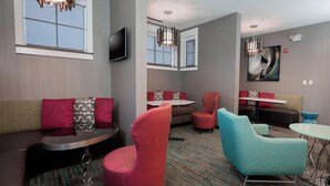 A modern hotel lobby with a sofa, chairs, a small table, and a TV mounted on the wall. - Residence Inn by Marriott Dallas Arlington South (Arlington)