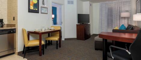 Une chambre d’hôtel comprenant un coin repas, une télévision, un canapé et une lampe.