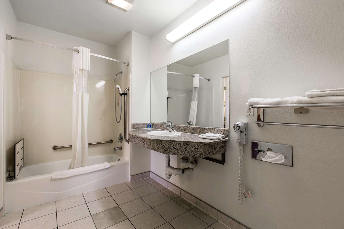 A bathroom with a bathtub, shower, and a vanity with a mirror.
