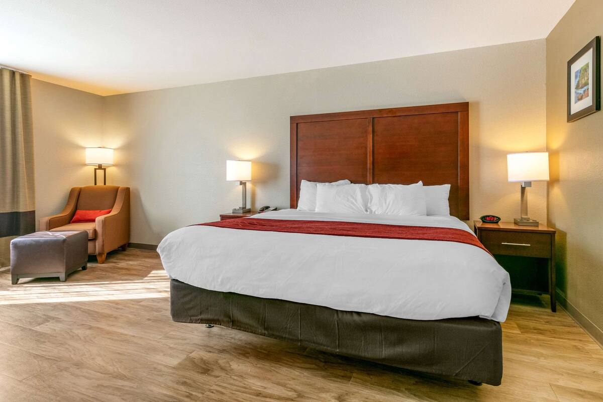 A hotel room with a large bed, two bedside tables, a chair, and a small table.