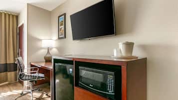 Une chambre d’hôtel équipée d’un bureau, d’une chaise, d’un four à micro-ondes et d’un téléviseur à écran plat fixé au mur.