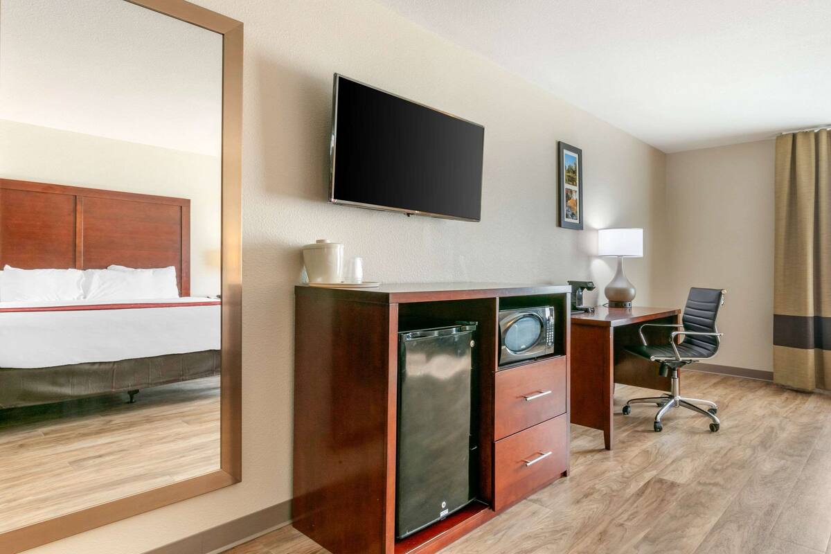 A hotel room with a bed, a desk with a computer, a television, and a microwave.