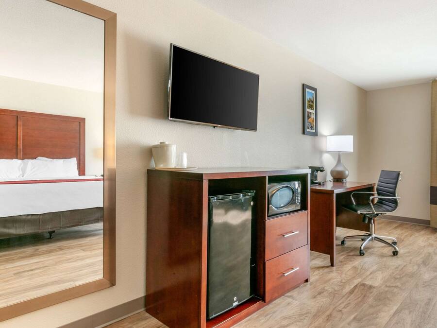 Une chambre d’hôtel équipée d’un lit, d’un bureau avec un ordinateur, d’une télévision et d’un four à micro-ondes.