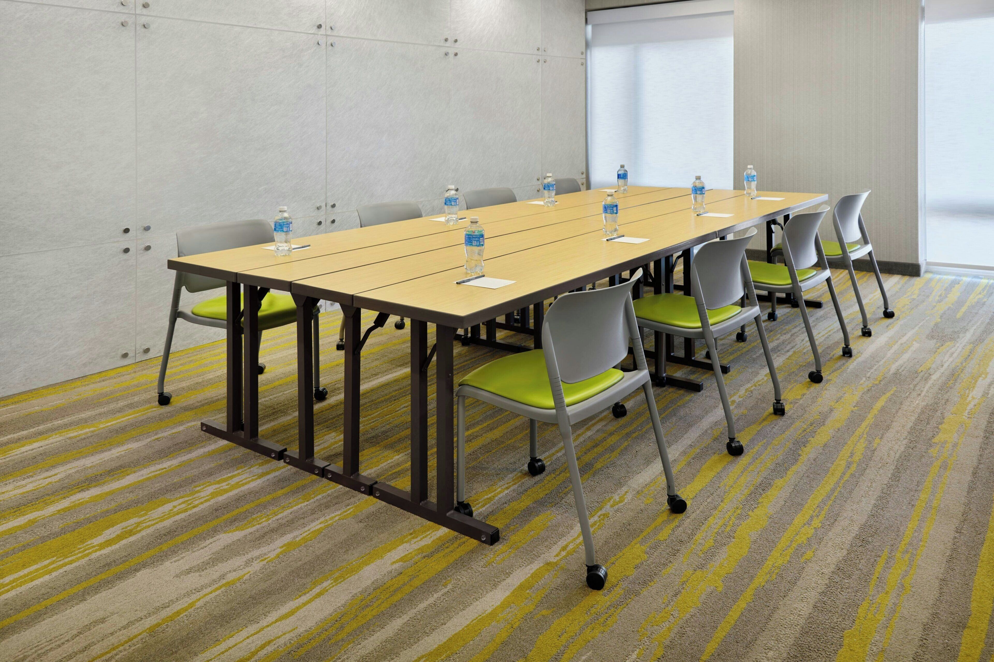 A conference room with a long table, chairs, water bottles, and a carpeted floor.