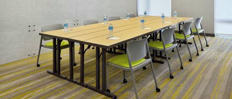 A conference room with a long table, chairs, water bottles, and a carpeted floor.
