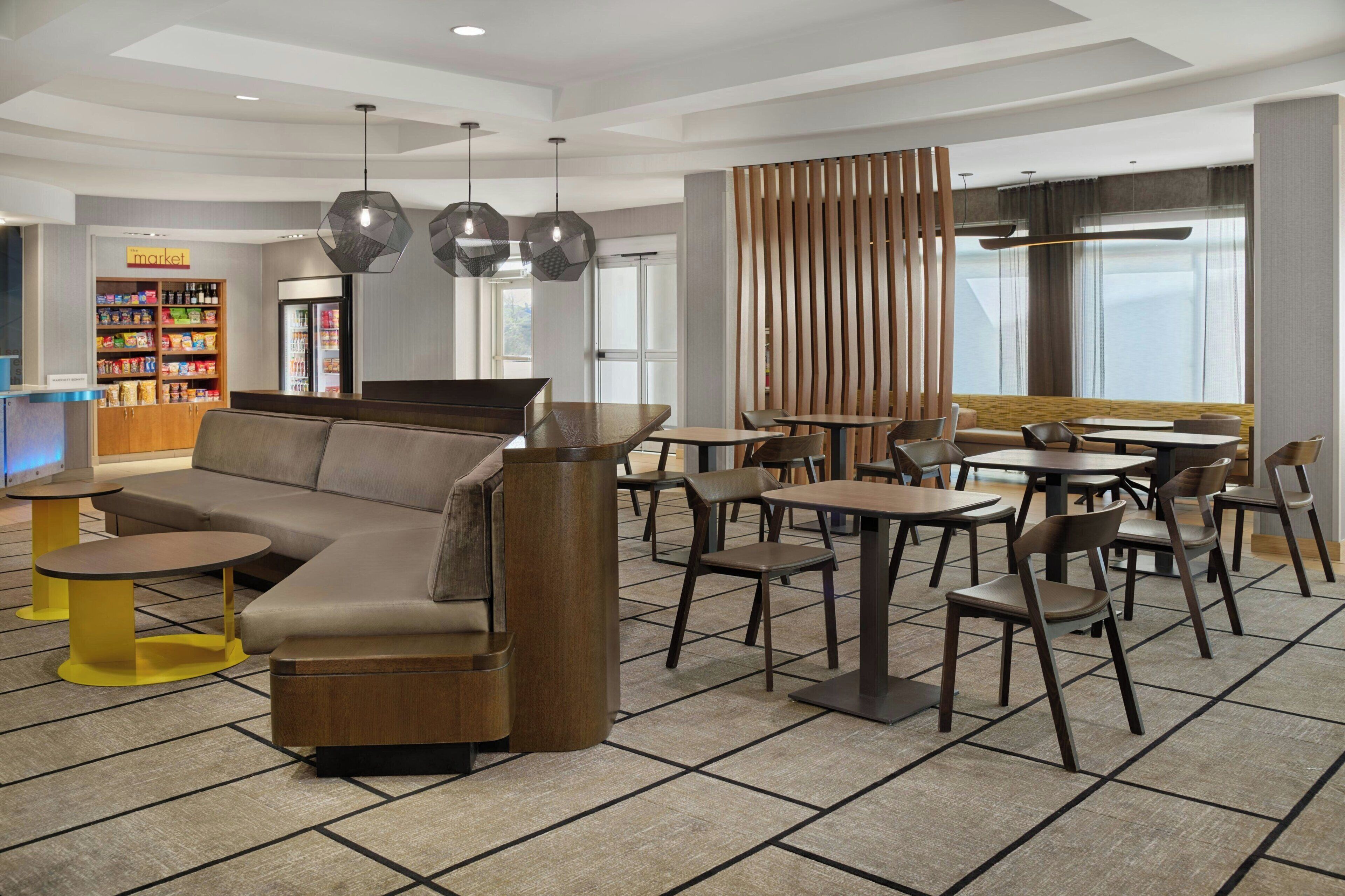 Eine moderne Lounge mit einer Couch, Tischen, Stühlen und einem Automaten.