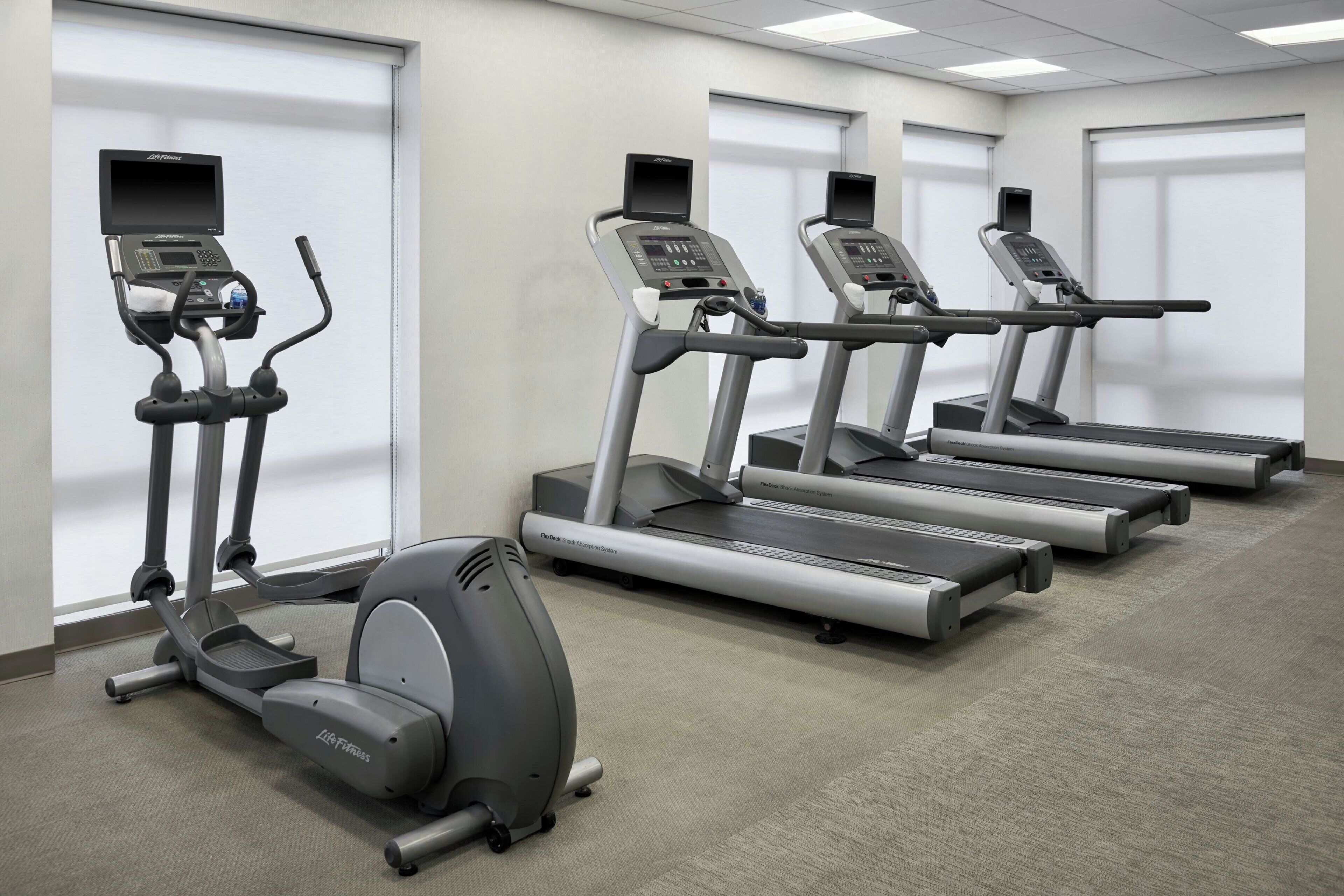 A fitness center with treadmills, an elliptical, and a stationary bike, all equipped with digital displays.