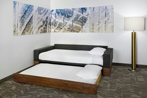Una habitación con cama, lámpara y un cuadro abstracto grande en la pared.