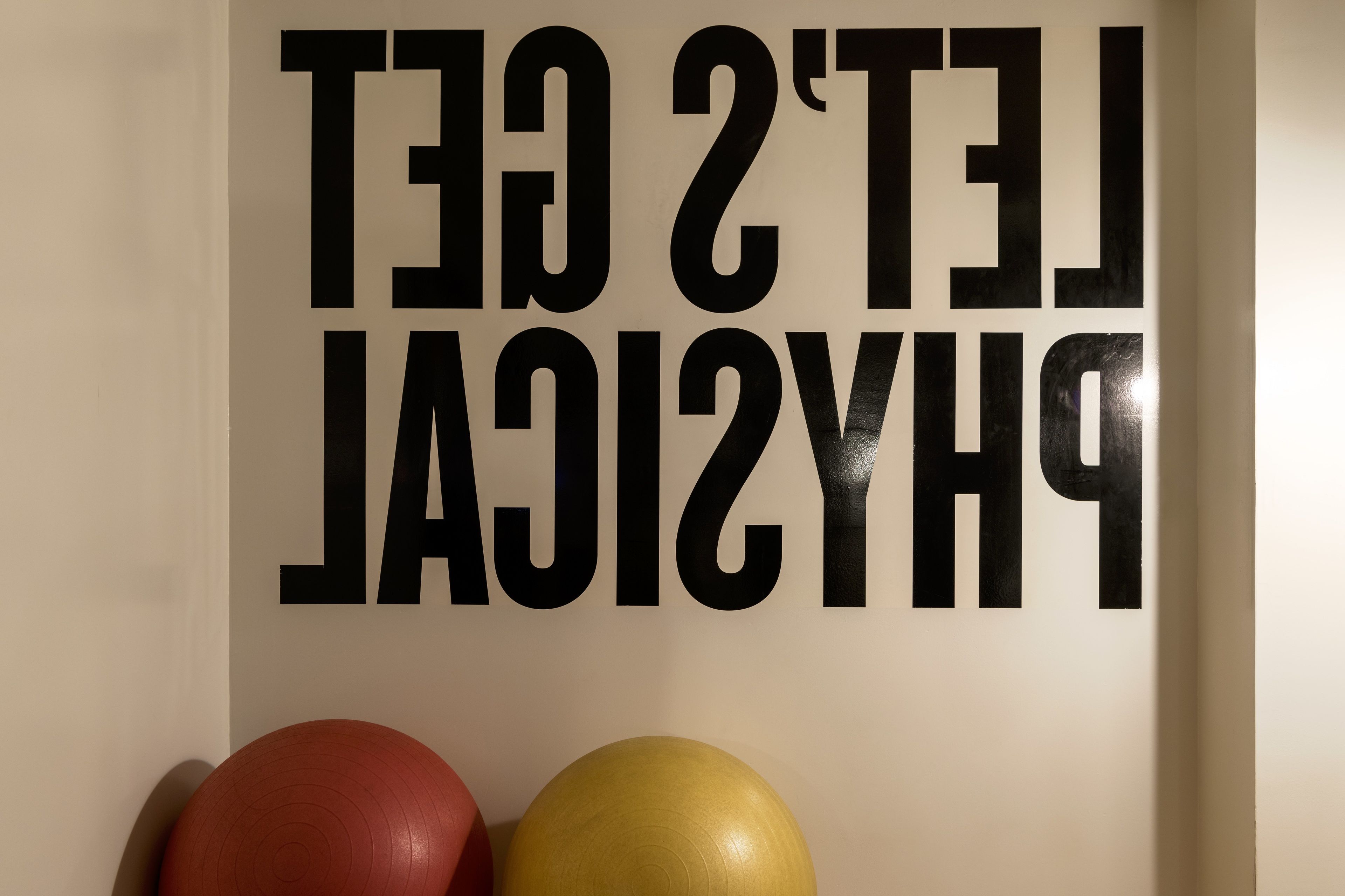 A wall with the text "THE 2ND GYM" and two exercise balls, one red and one yellow.