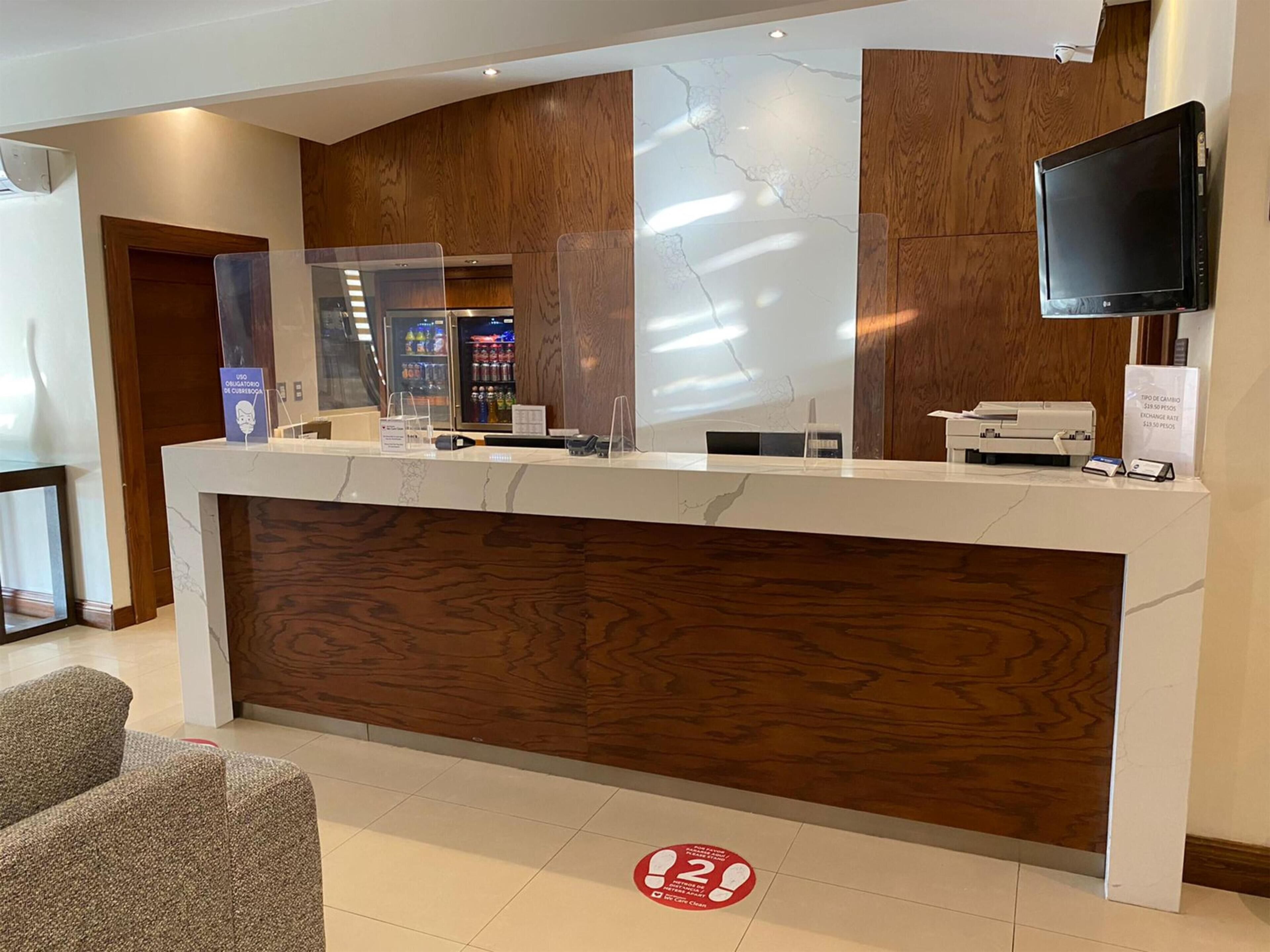 A reception desk with a wooden panel design, a glass partition, and a flat-screen TV mounted on the wall.