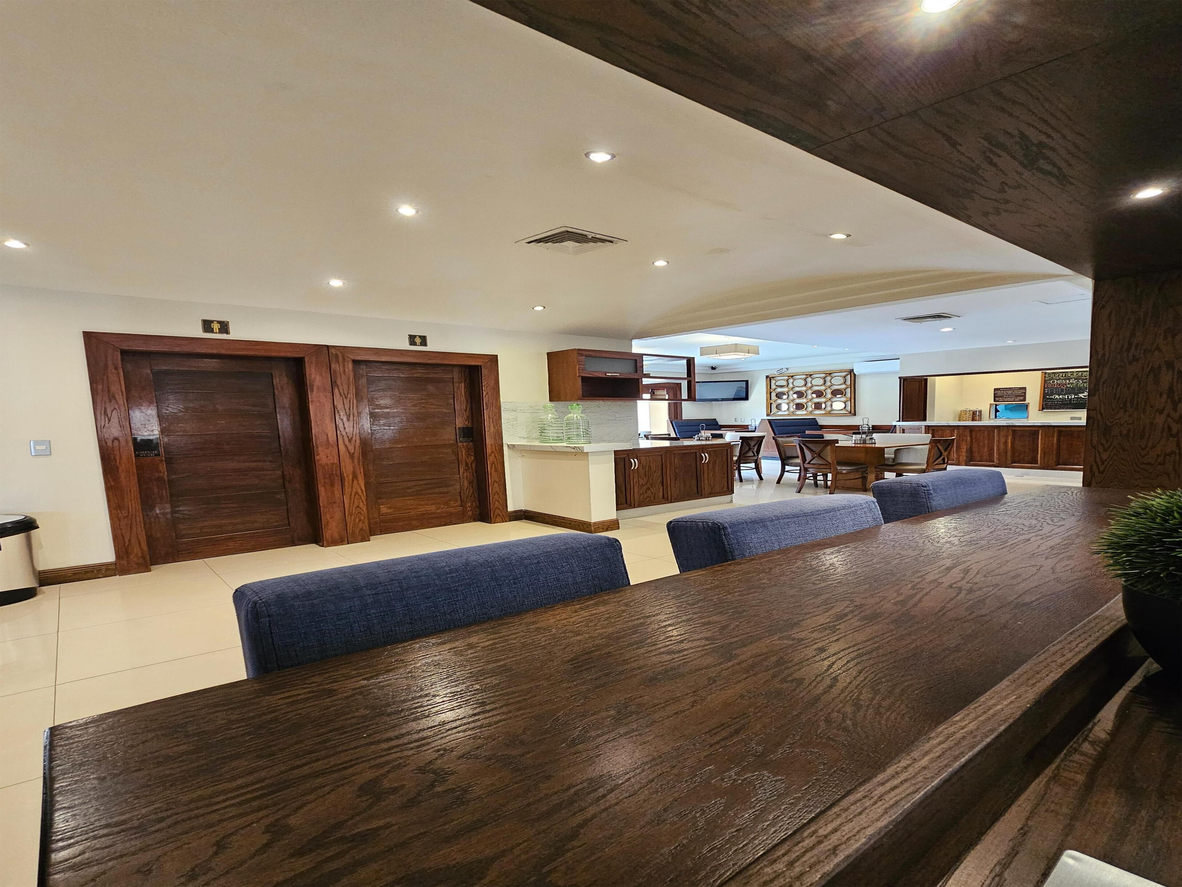 Uma área de refeições moderna com uma mesa de madeira comprida e bancos estofados em azul.