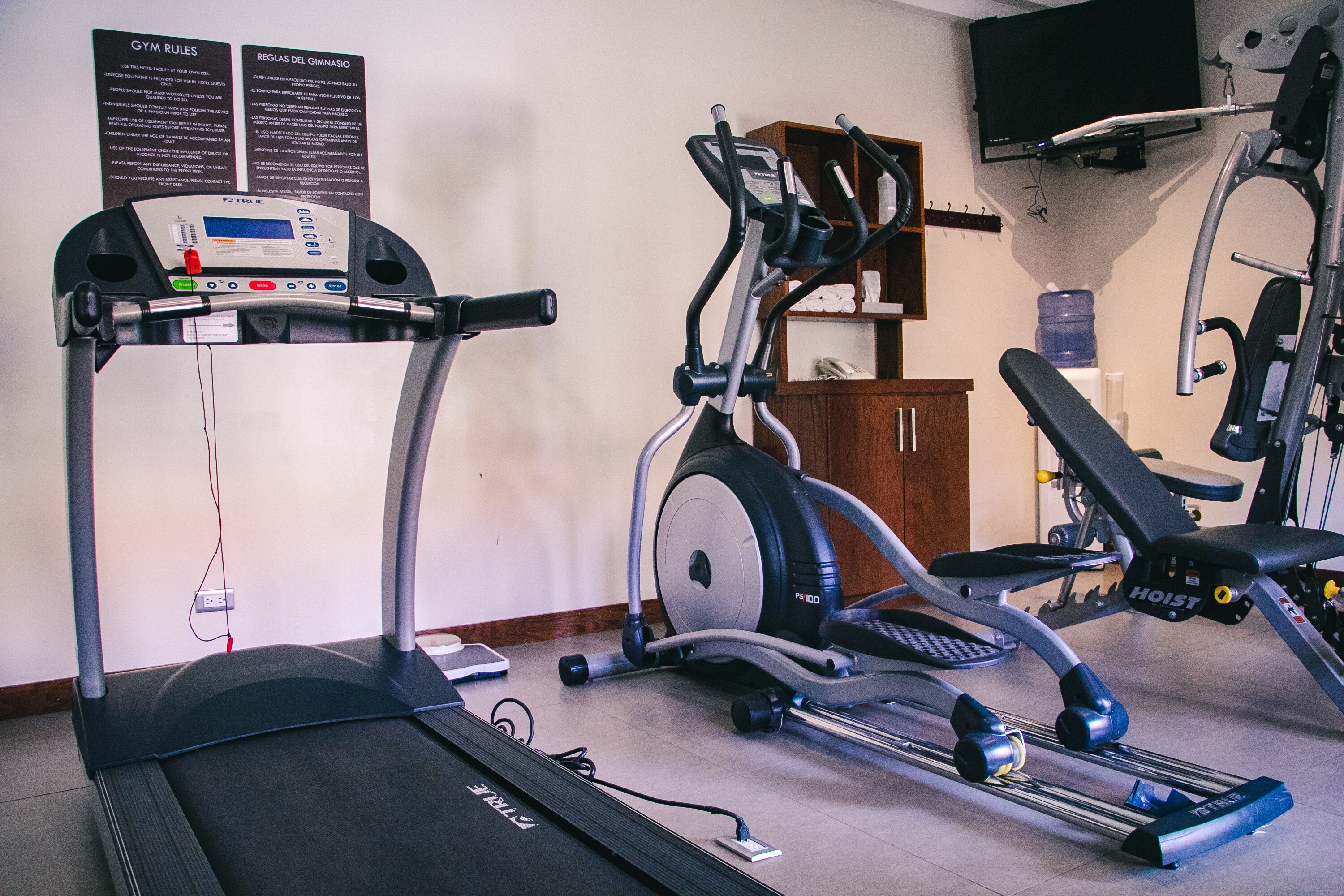 A gym with treadmills, elliptical machines, and a weight bench.