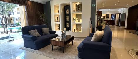 A modern living room with two sofas, a coffee table, and built-in shelving with decorative items.