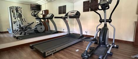 A gym with a treadmill, elliptical, and stationary bike.