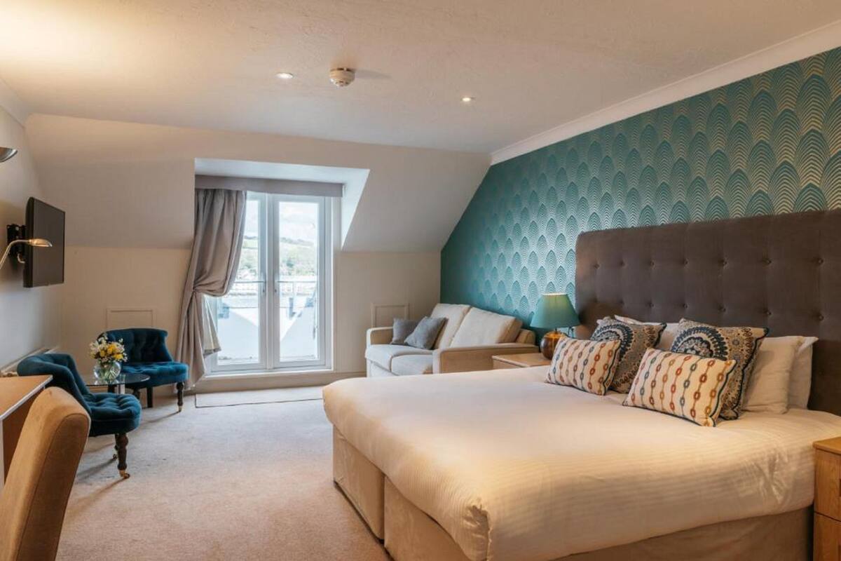 Une chambre avec un grand lit, un canapé, un fauteuil et une télévision.