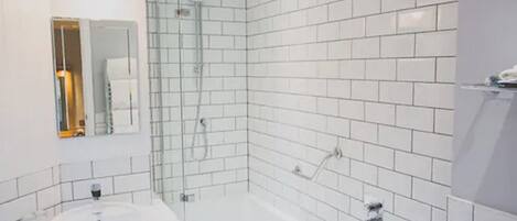 A modern bathroom with white subway tiles, a round sink, and a glass-enclosed shower.