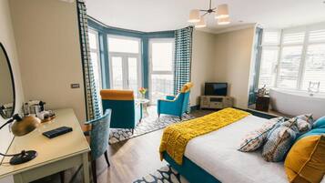 A hotel room with a bed, a desk, a chair, a TV, and a balcony with a view.