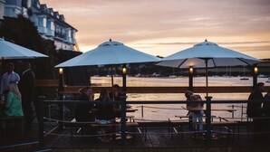 Un ristorante sul lungomare con posti a sedere all'aperto, ombrelloni e vista sull'acqua.