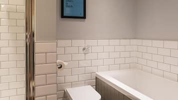 A bathroom with white tiled walls, a toilet, and a bathtub.