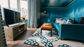 Ein modernes Wohnzimmer mit einem großen Flachbildfernseher, einem blauen Sofa und einem gemusterten Teppich.