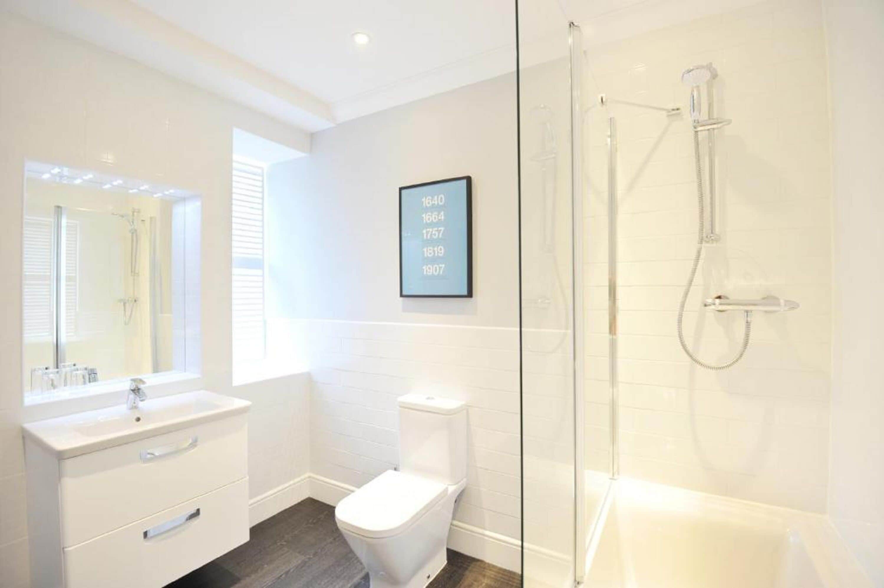 A modern bathroom with a glass-enclosed shower, a white sink, and a toilet.