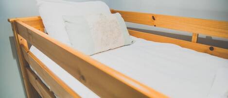 Ein Bett aus Holz mit weißer Bettwäsche und einem Kopfkissen.