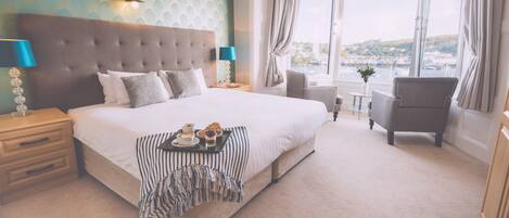 A hotel room with a large bed, a view of the city, and a window with curtains.