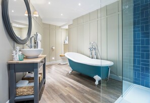 A modern bathroom with a freestanding bathtub, a large mirror, and a wooden vanity.