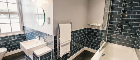 Un baño moderno con una bañera grande, dos lavamanos y una zona de ducha con mampara de vidrio.