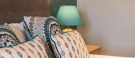 A neatly made bed with patterned pillows and a bedside lamp.
