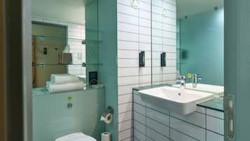Un baño moderno con cabina de ducha de vidrio, inodoro blanco y lavamanos con espejo.