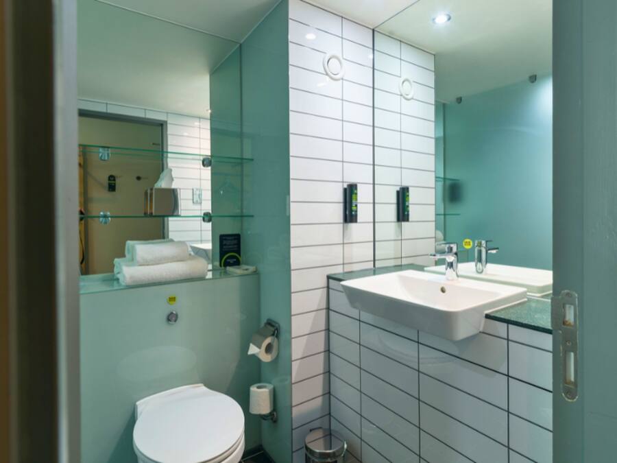 A modern bathroom with a glass shower enclosure, a white toilet, and a sink with a mirror above it.