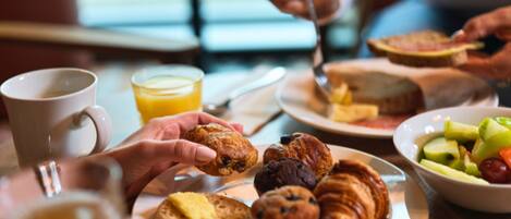 A breakfast setting with pastries, a muffin, and a bowl of fruit on a table.
