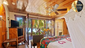 A room with a bed, a TV, a chair, and a view of palm trees. - Portofino Beach Resort (San Pedro)